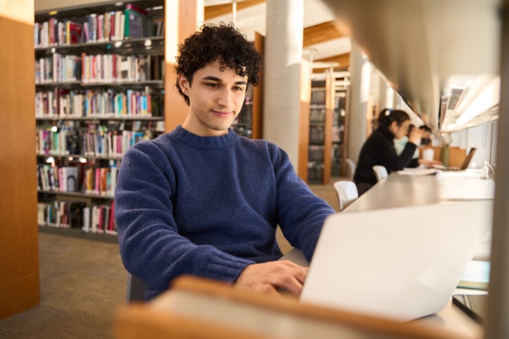 Menino usando computador em biblioteca