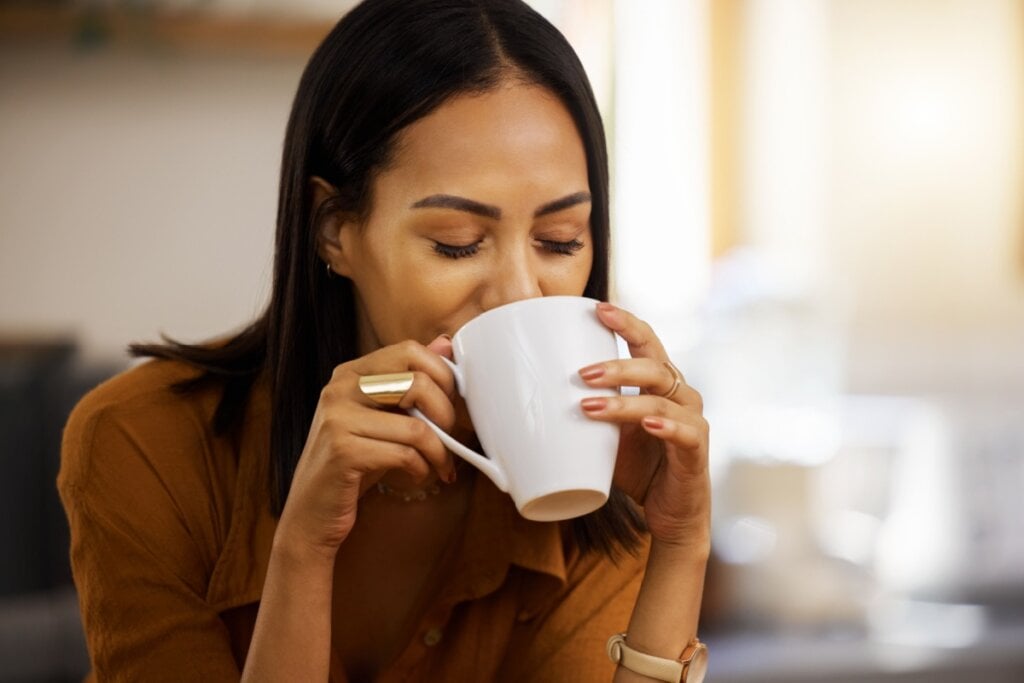 Mulher bebendo chá com uma expressão satisfeita 