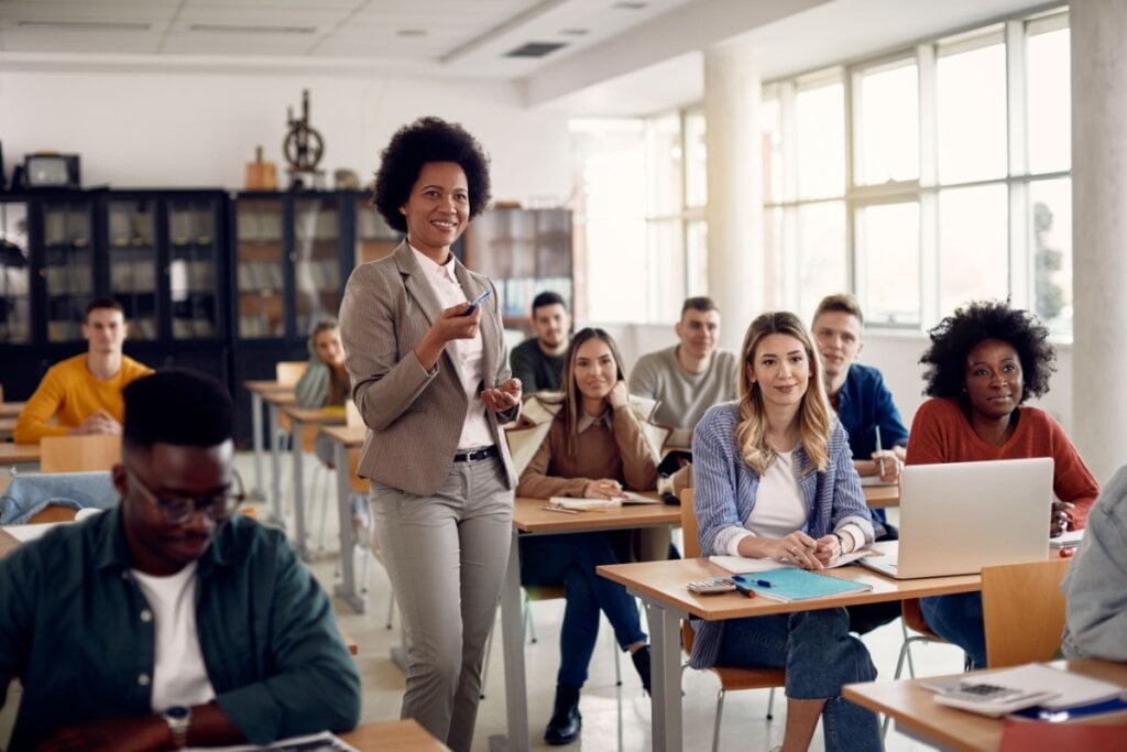 professora em pé e alunos sentados em sala de aula