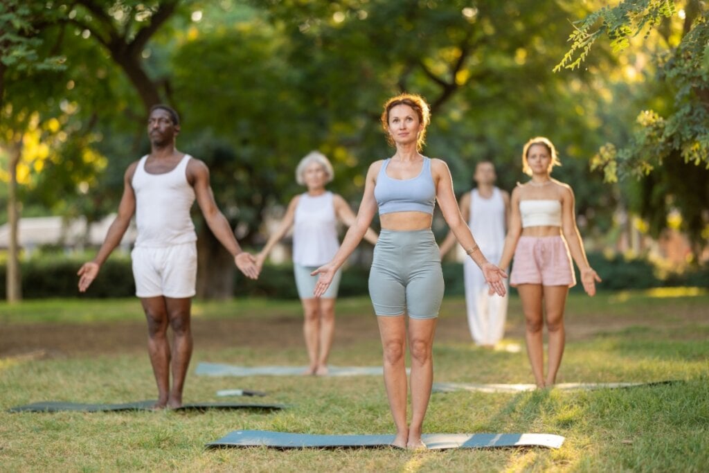 cinco pessoas em parque fazendo tadasana