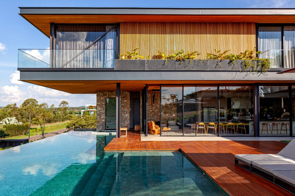 área externa de piscina com borda infinita e deck de madeira 