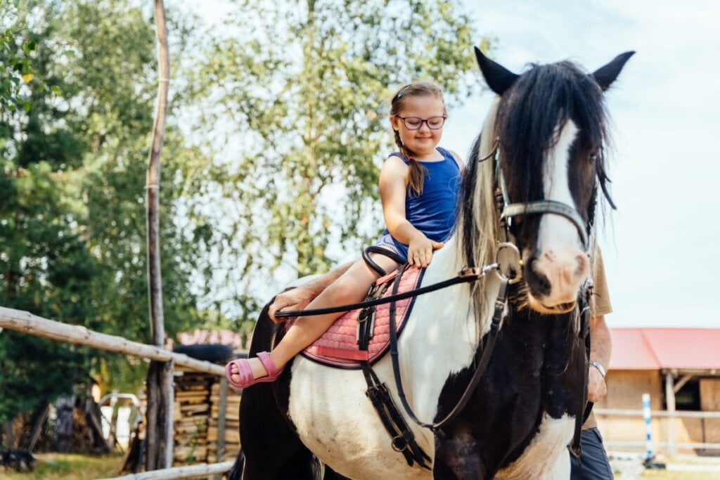 menina em cima de cavalo branco e preto