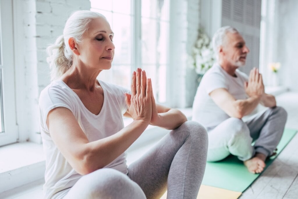 Casal de idoso meditando sentados no chão