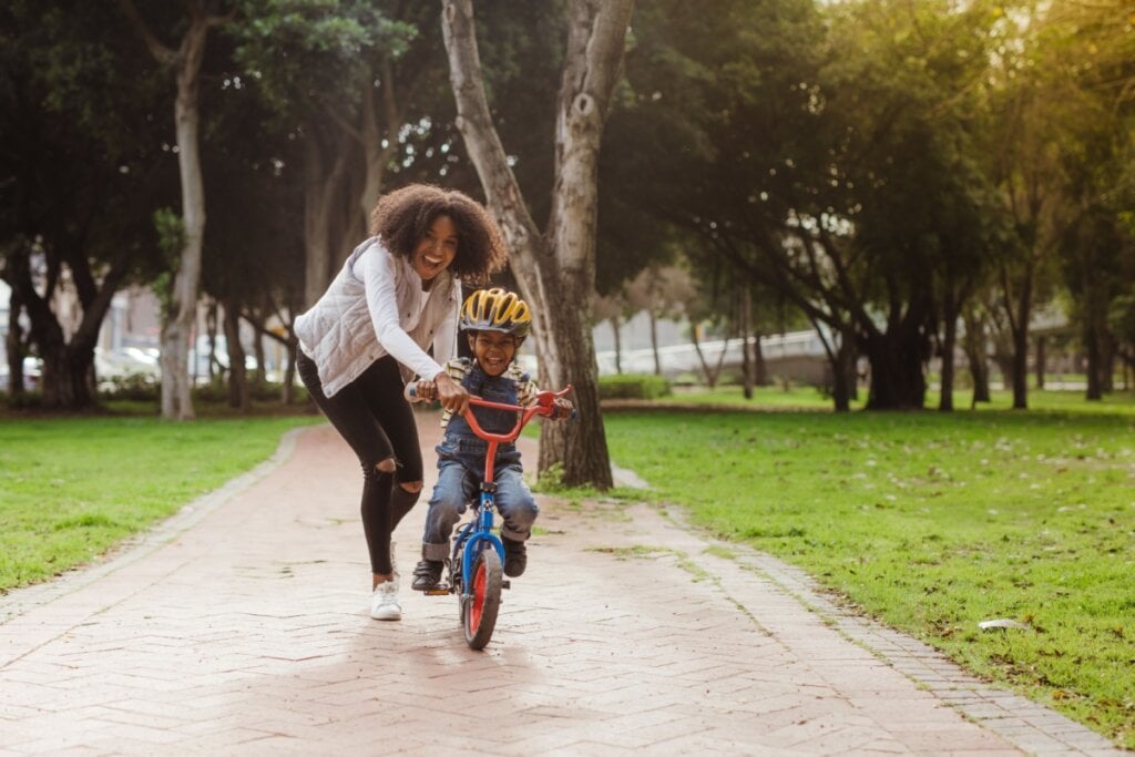 Mãe ajudando o filho a andar de bicicleta no parque 