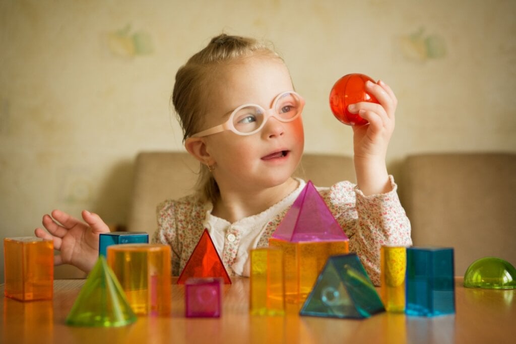 menina com Síndrome de Down brincando com blocos de brinquedo