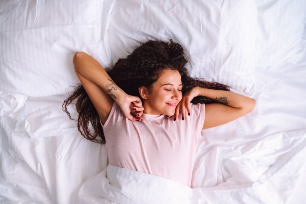 Mulher se espreguiçando na cama 