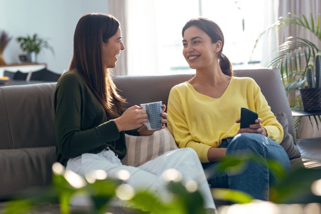 Duas mulheres conversando e rindo em sofá