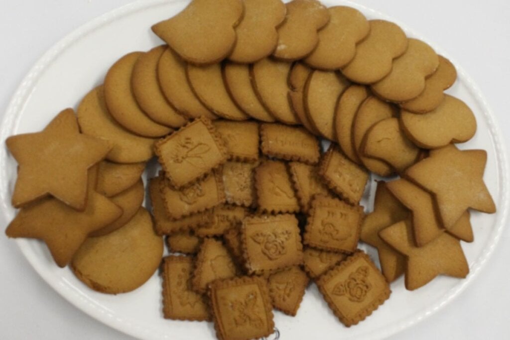 Biscoitos de melado em formato de estrelas, coração, retângulo e triângulo em um prato branco