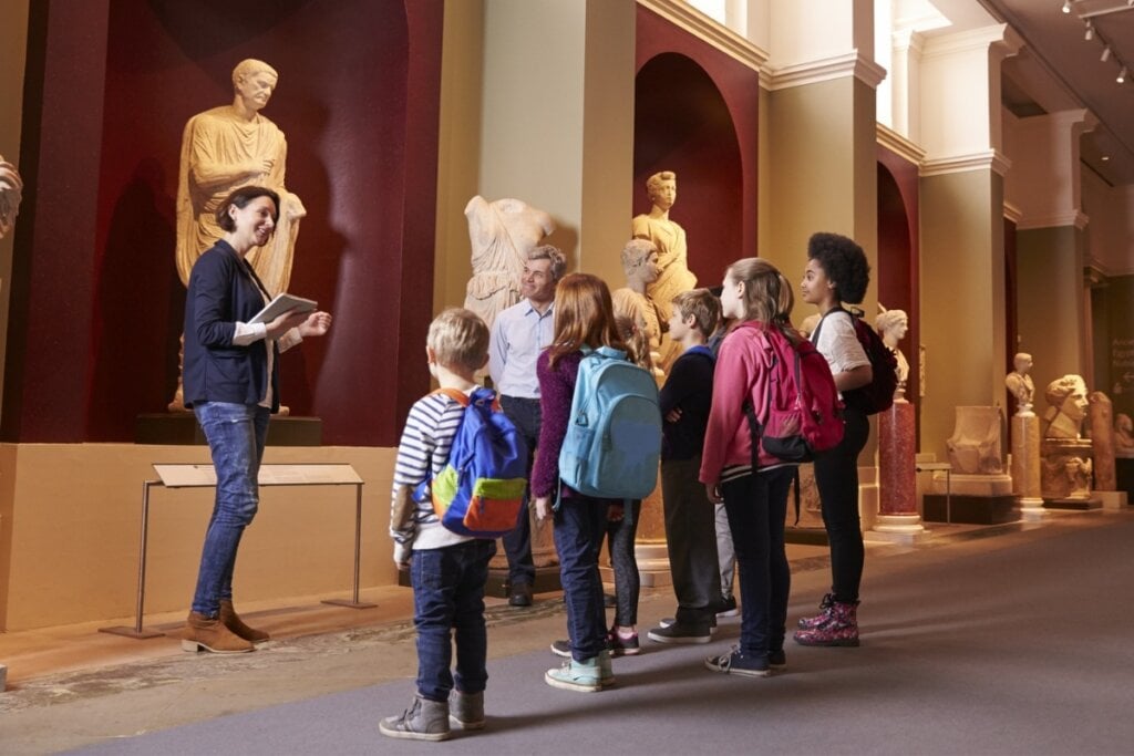 Mulher em um museu falando com crianças 