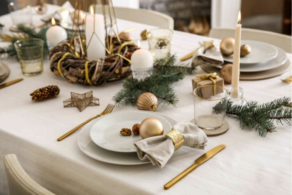 Mesa com toalha branca, prato branco e talheres dourados