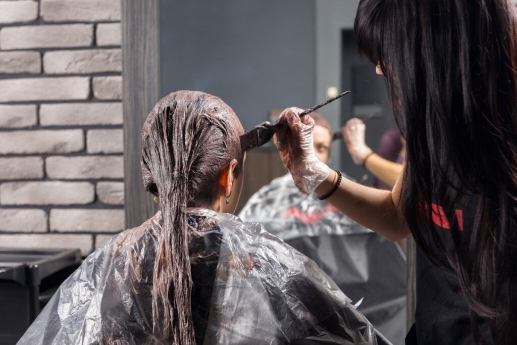 Mulher pintando o cabelo de uma mulher sentada 