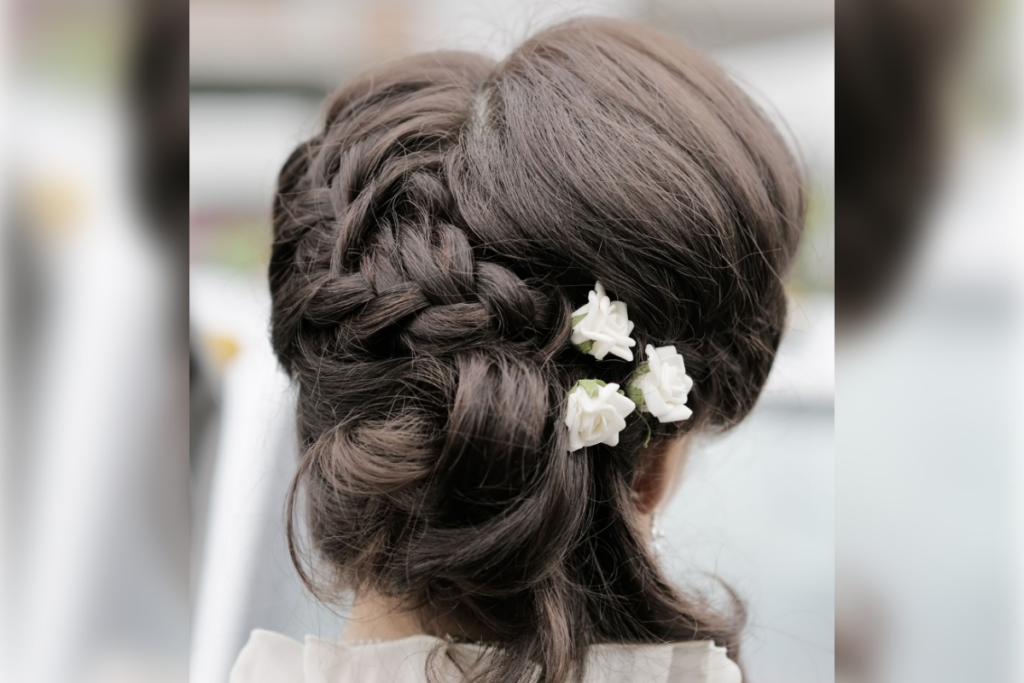 Penteado preso na parte de trás da cabeça, com tranças entrelaçadas e pequenas flores brancas