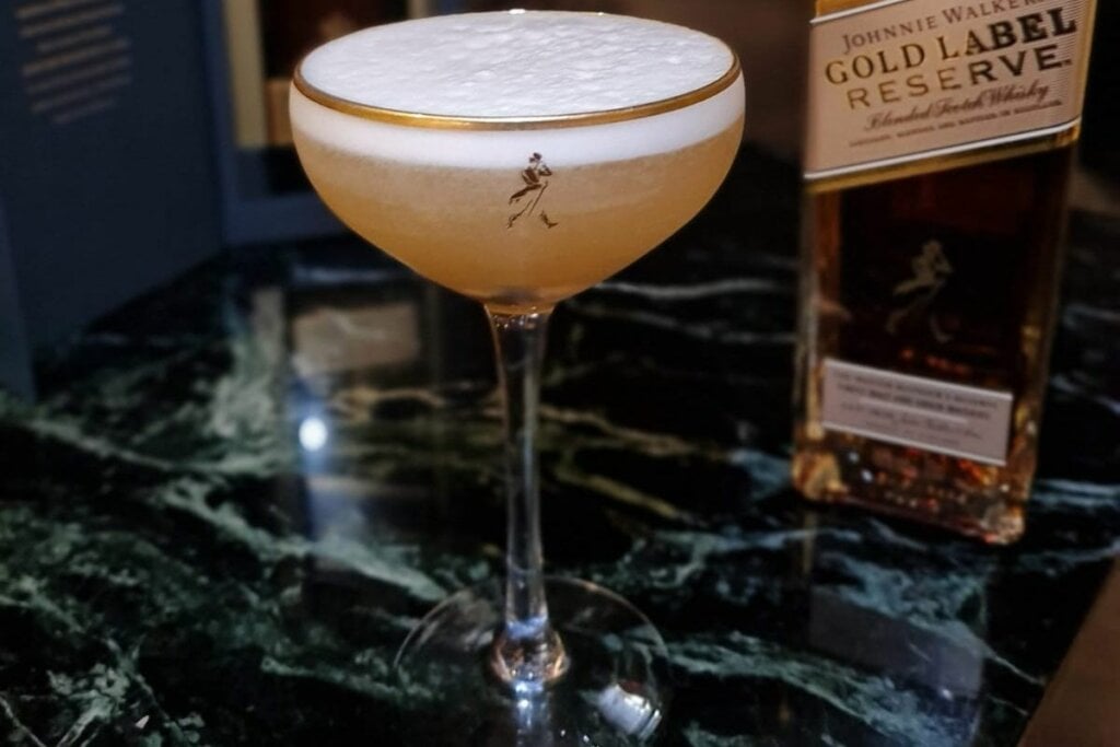 Whisky Sour em uma taça em cima de uma mesa de mármore