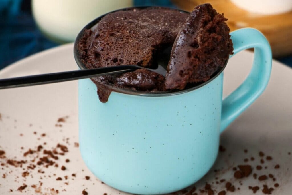 Bolo de chocolate em uma caneca azul com uma colher 