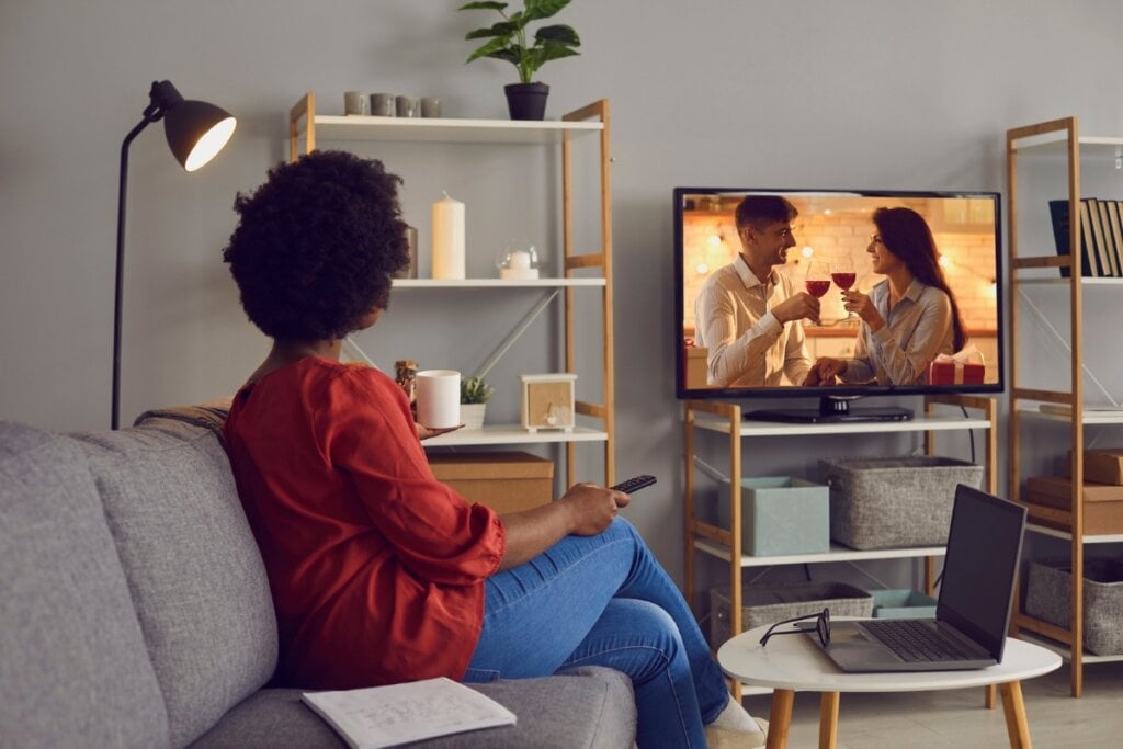 Mulher sentada em um sofá assistindo televisão 