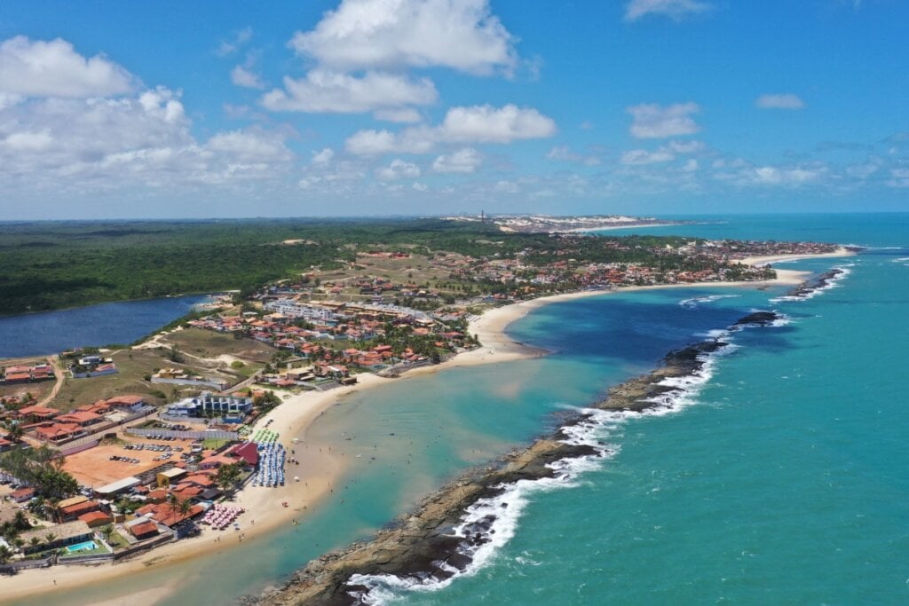 Vista aérea da Praia de Camurupim, com suas águas calmas, piscinas naturais formadas por recifes de corais e uma extensa faixa de areia