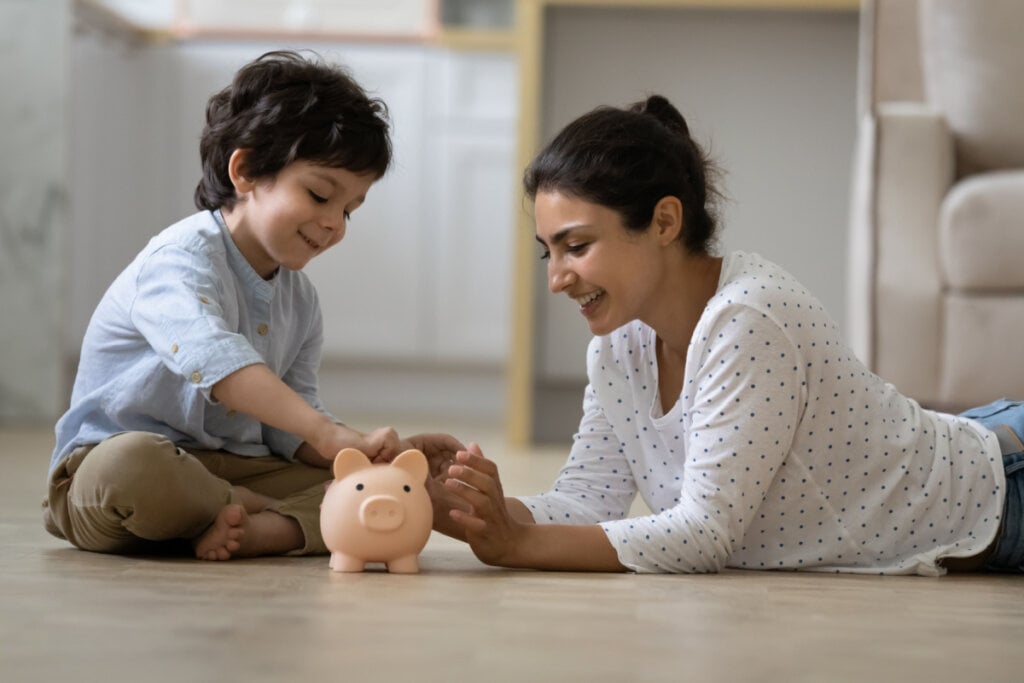 Mãe e filho colocando moedas em cofre de porquinho