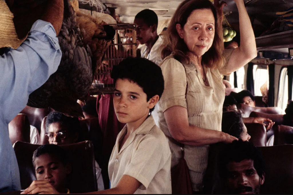 Imagem focada em mulher e menino dentro de ônibus cheio de pessoas 