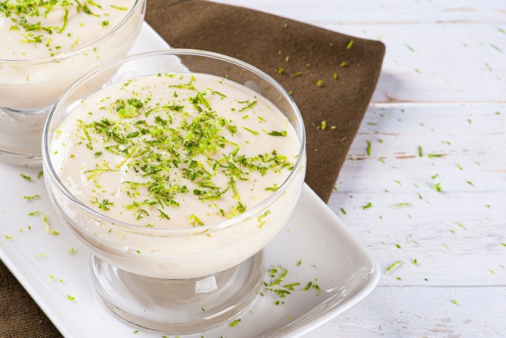 Mousse de maracujá com raspas de limão servido em taça em cima de mesa de madeira