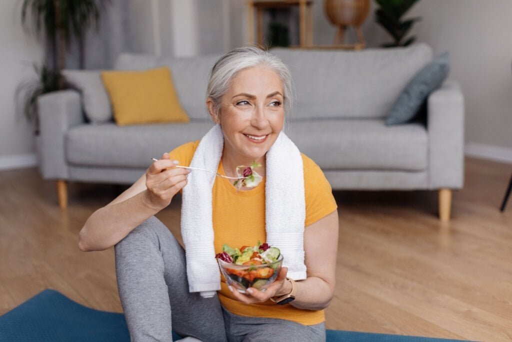 Mulher mais velha comendo salada após praticar exercício