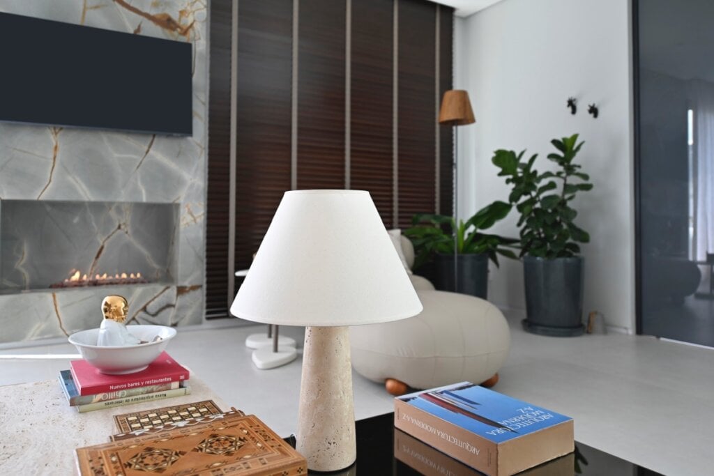 Sala de estar com mesa de centro em madeira maciça e luminária de mesa em pedra, complementada por plantas e acabamentos naturais