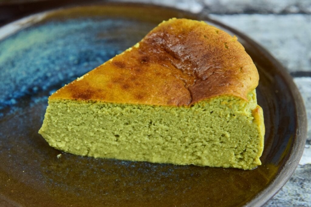 Pedaço de bolo verde em cima de um prato marrom 