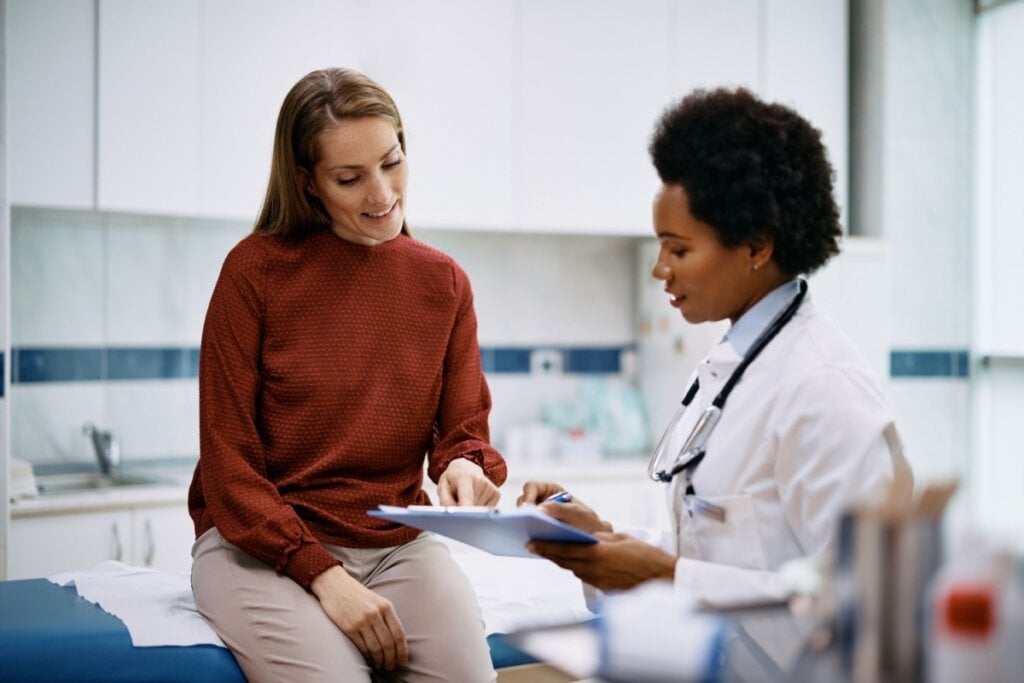 Mulher sentada em um consultório conversando com uma médica