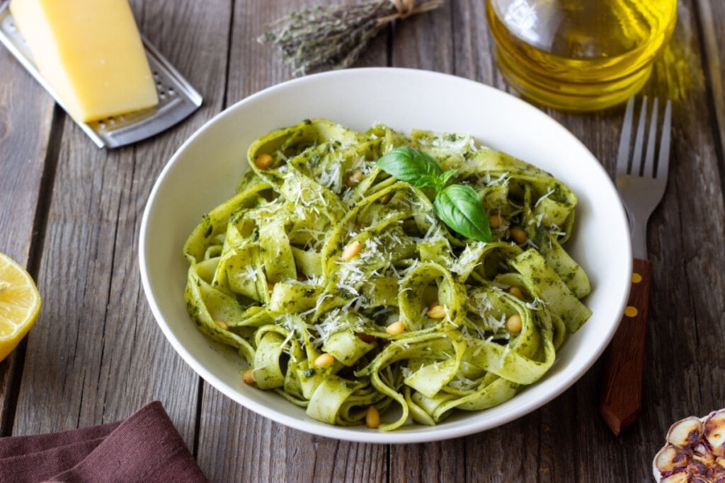 prato fundo branco com fettuccine ao molho pesto com queijo e azeite ao lado