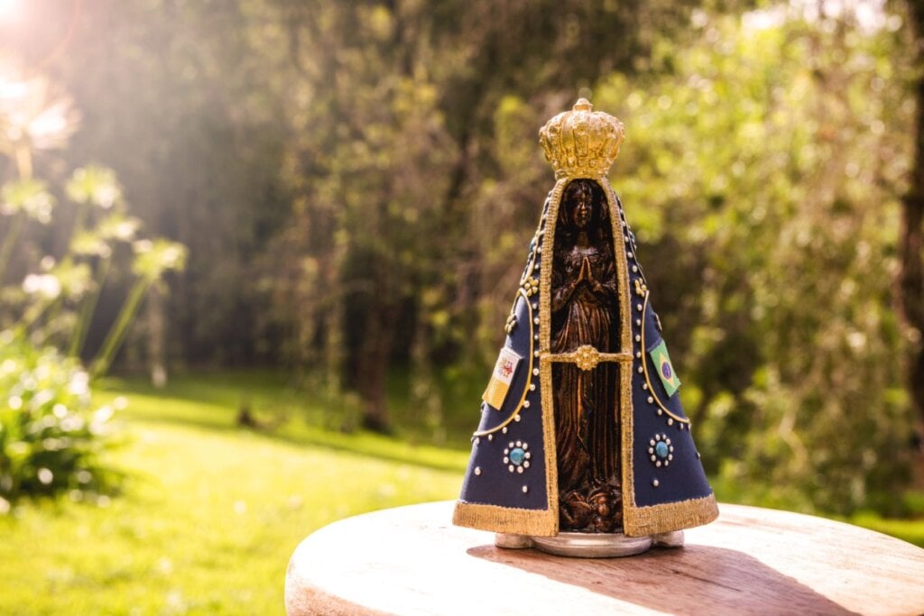 Imagem de Nossa Senhora Aparecida em bancada de madeira ao ar livre