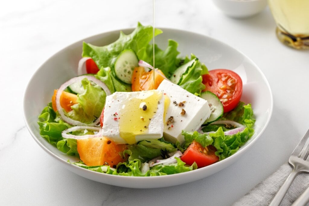 Recipiente branco com alface, tomate, cebola e queijo