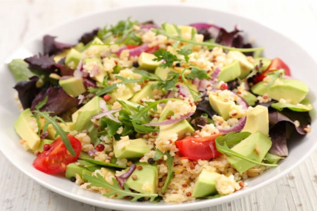 Salada de quinoa com abacate e tomate em prato branco