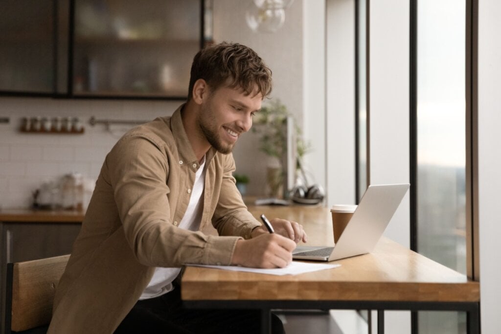 Homem assistindo curso e fazendo anotações