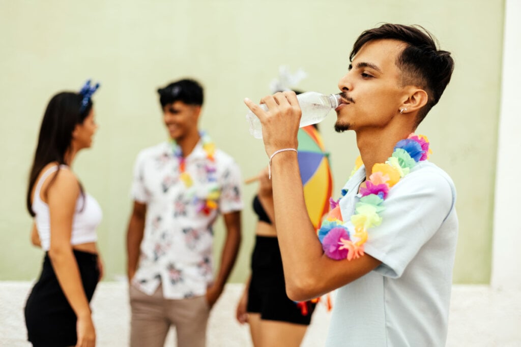 Menino bebendo água em garrafa durante Carnaval