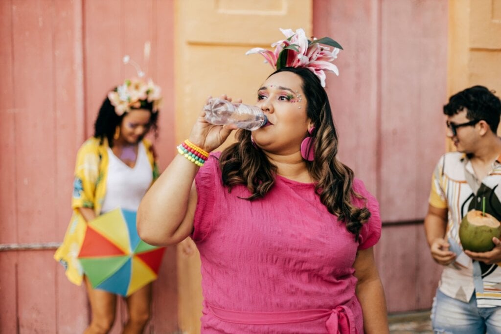 Mulher bebendo água em festa de Carnaval