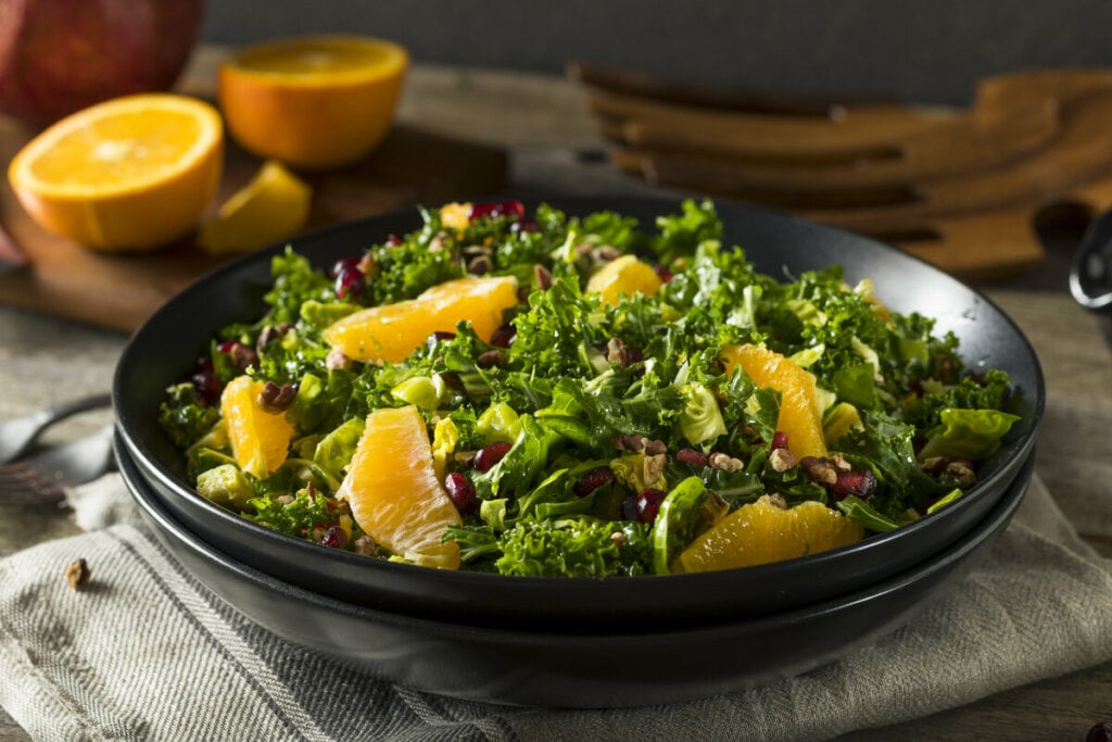 Prato preto com salada de couve com laranja e sementes de romã