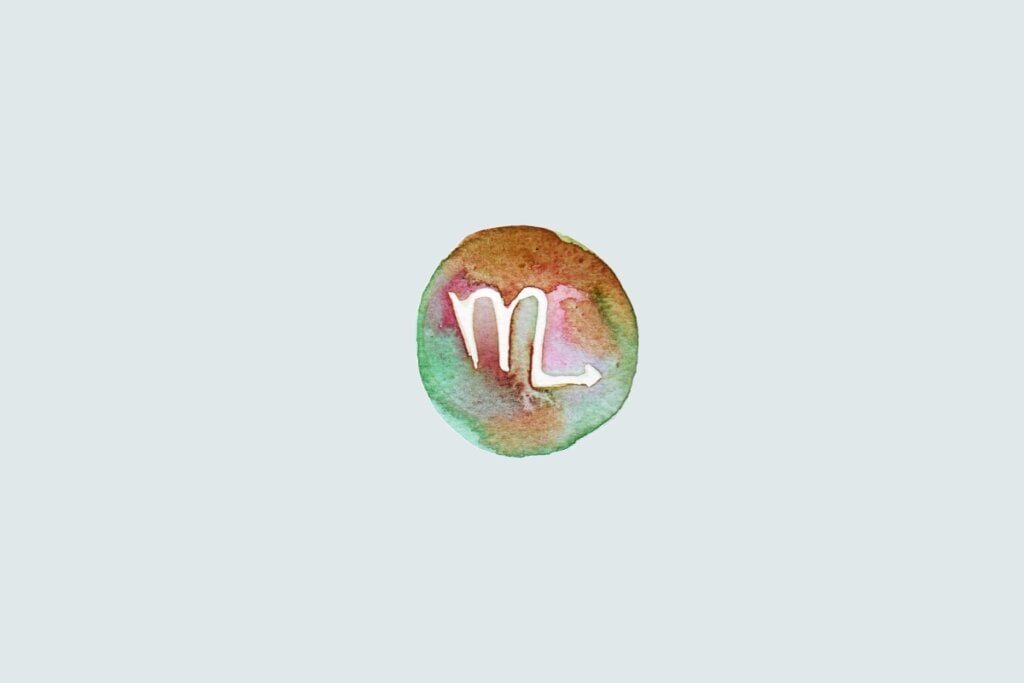 Símbolo do signo de Escorpião em forma de “M” com cauda voltada para cima, sobre fundo colorido em estilo aquarela