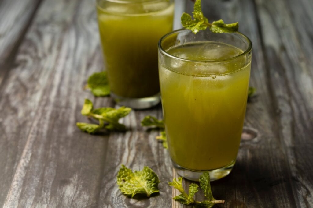 Dois copos de vidro com suco de hortelã em cima de uma mesa de madeira 