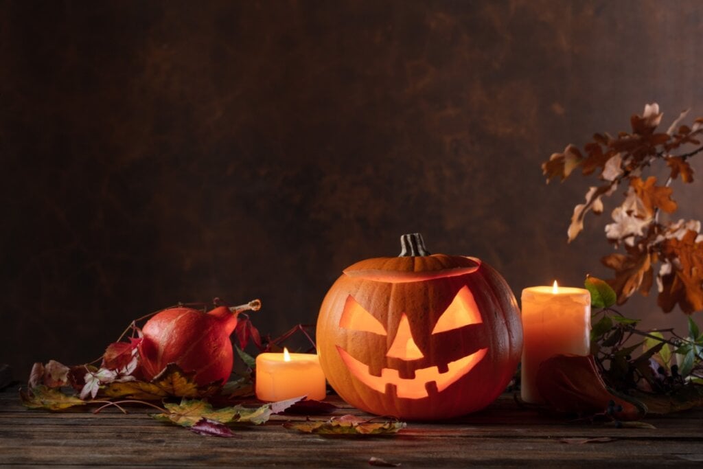 abóbora de Halloween com luz laranja e velas laranjas em volta