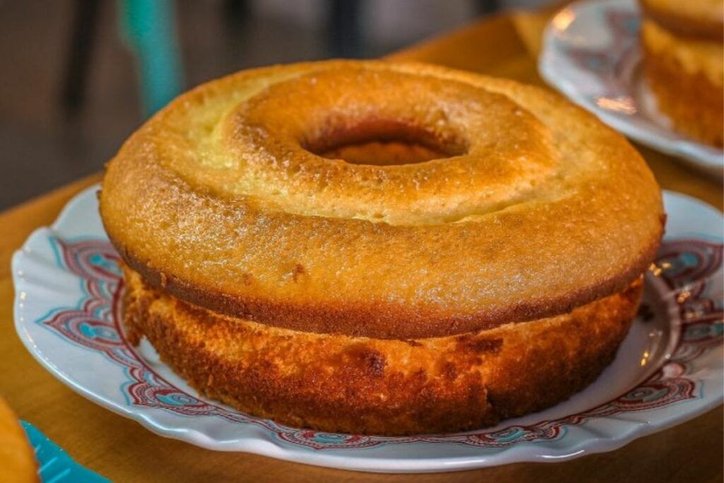 Bolo de fubá redondo com furo no meio em cima de prato branco