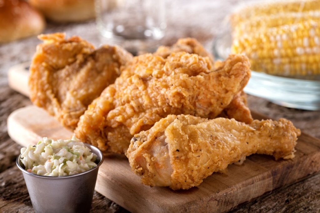 7 receitas práticas com frango para o almoço 6 Pedaços de frango empanado em cima de uma tábua de madeira