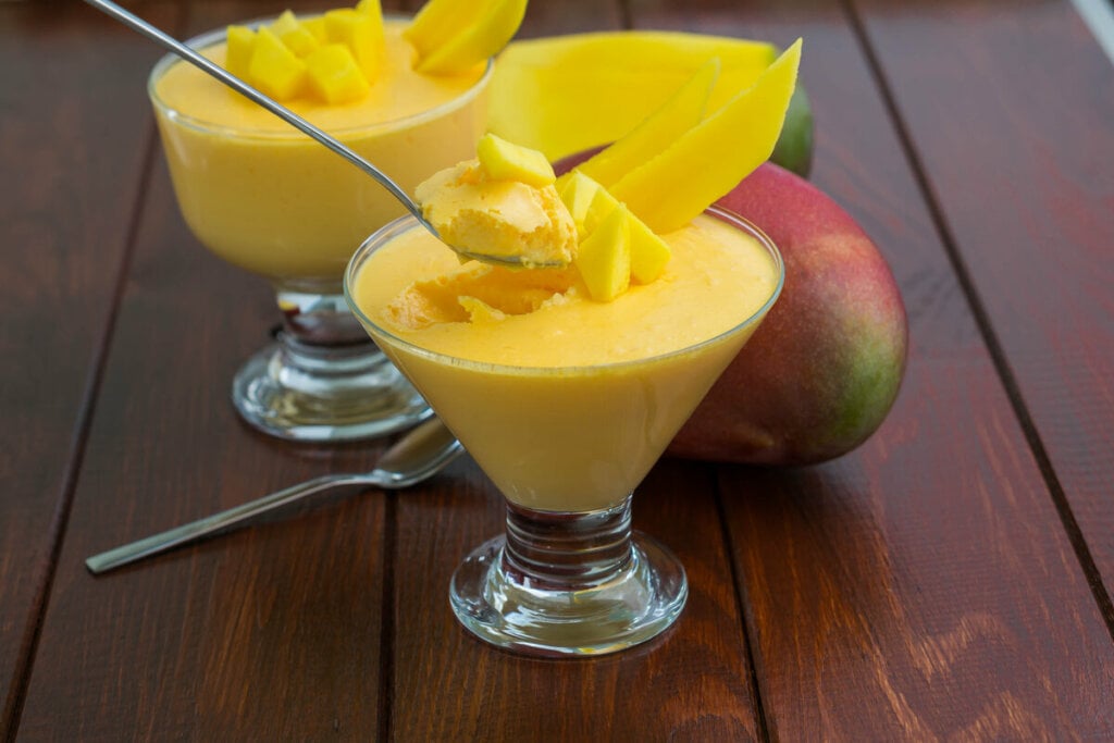 8 sobremesas incríveis e fáceis com manga 6 Taça de vidro com gelatina cremosa de manga e manga ao fundo