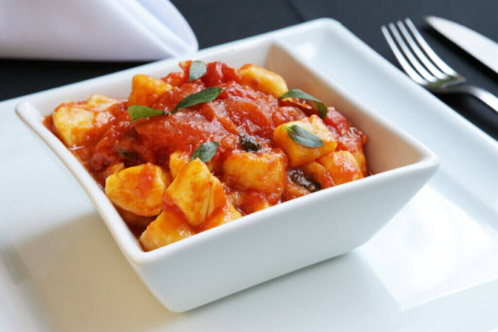 7 receitas veganas para o Dia das Mães 6 Nhoque de mandioquinha com molho de tomate servido em tigela branca em cima de bancada branca