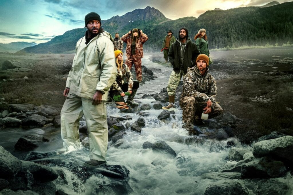 5 lançamentos imperdíveis da Netflix em junho de 2025 22 Capa da série "Sobreviventes" com pessoas em pé em um rio e com uma montanha ao fundo