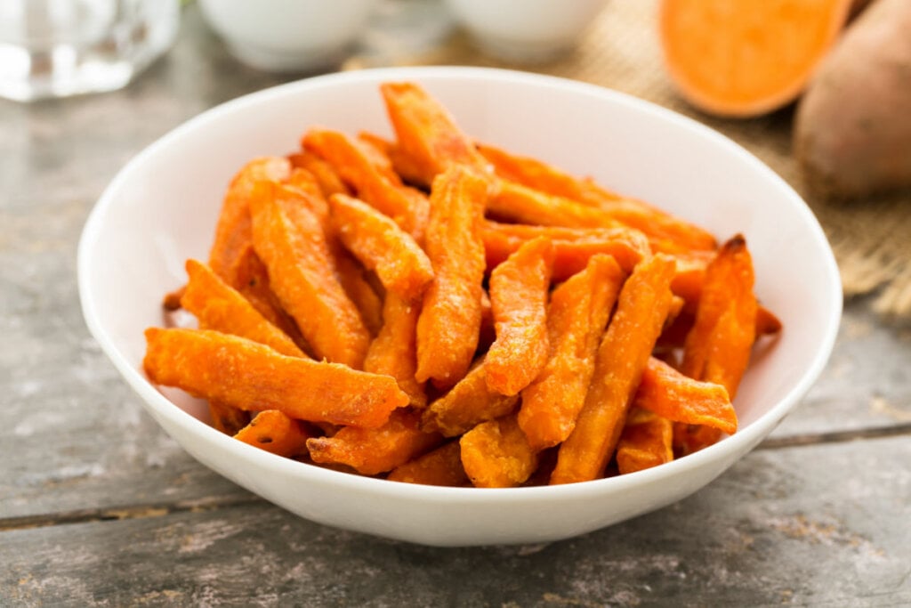 8 receitas vegetarianas rápidas para fazer na air fryer 6 Batata-doce frita em palitos servida em um bowl branco