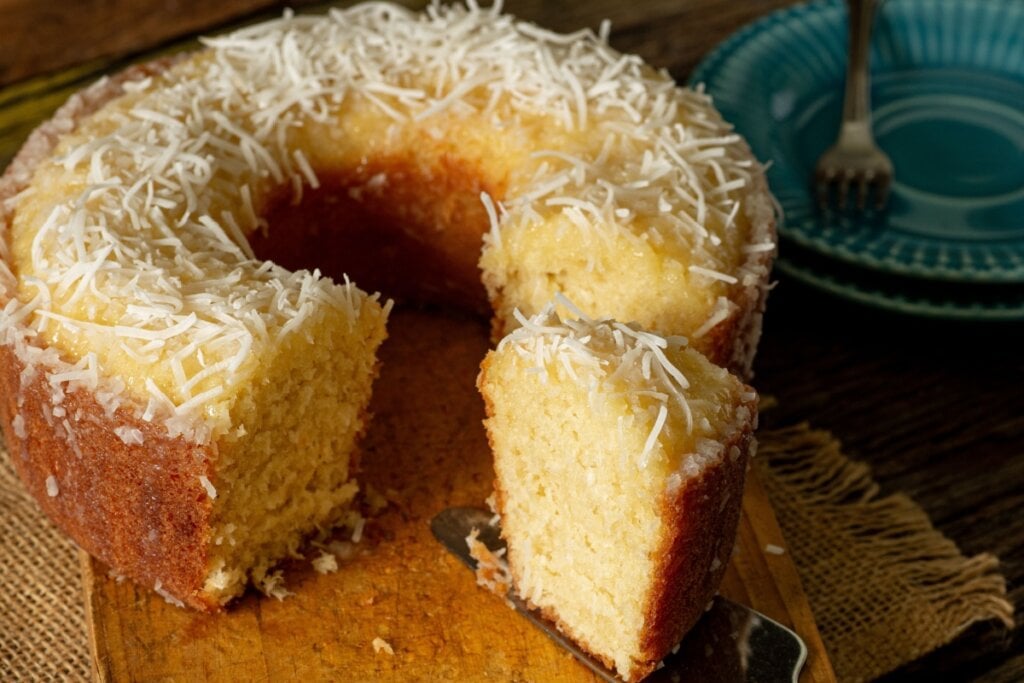 7 receitas de liquidificador para o fim de semana 6 Bolo de coco servido em cima de tábua de madeira em cima de mesa de madeira