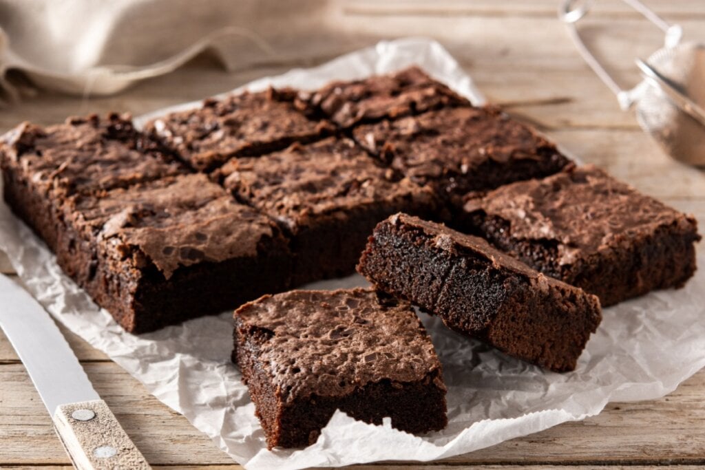 7 receitas veganas de liquidificador 6 Brownie servido em cima de papel manteiga em cima de mesa de madeira