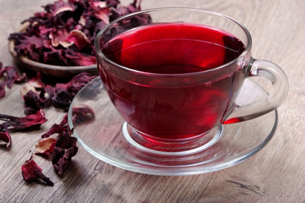 7 receitas de chás termogênicos para o inverno 6 Chá de hibisco com gengibre e laranja em xícara transparente em cima de uma mesa