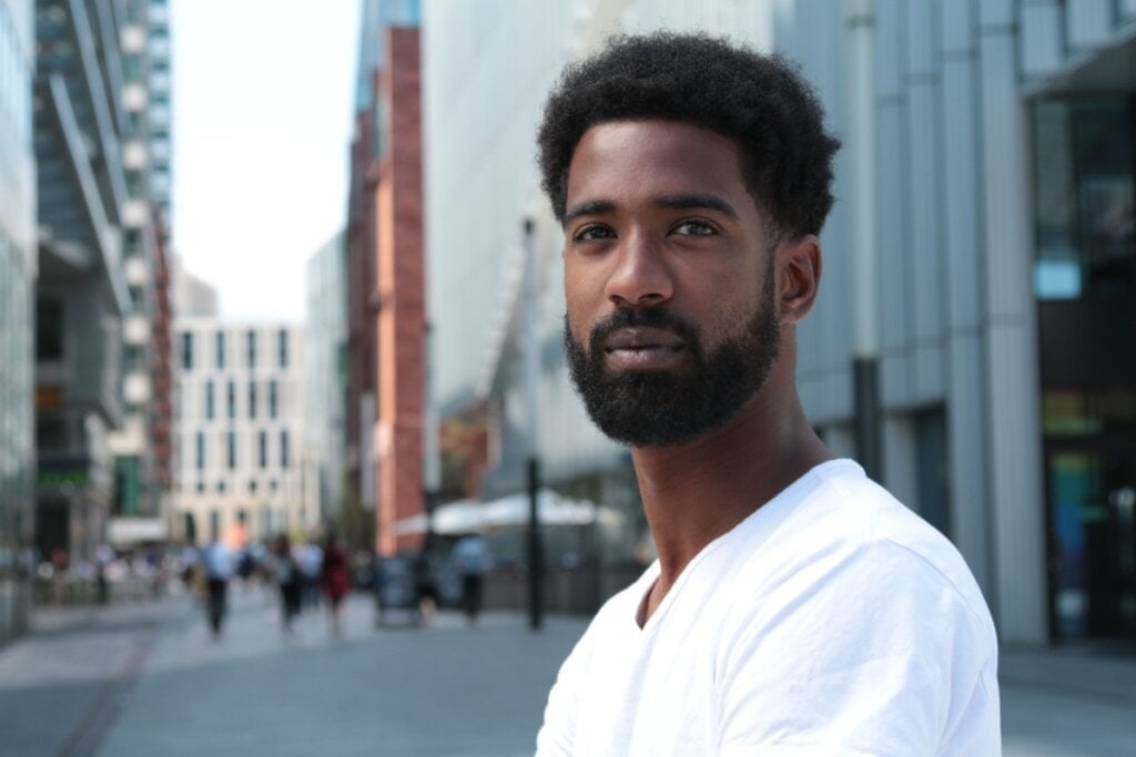 5 tendências de cortes para homens com cabelo cacheado 24 Homem olhando para a frente e com o corte de cabelo Fade Americano