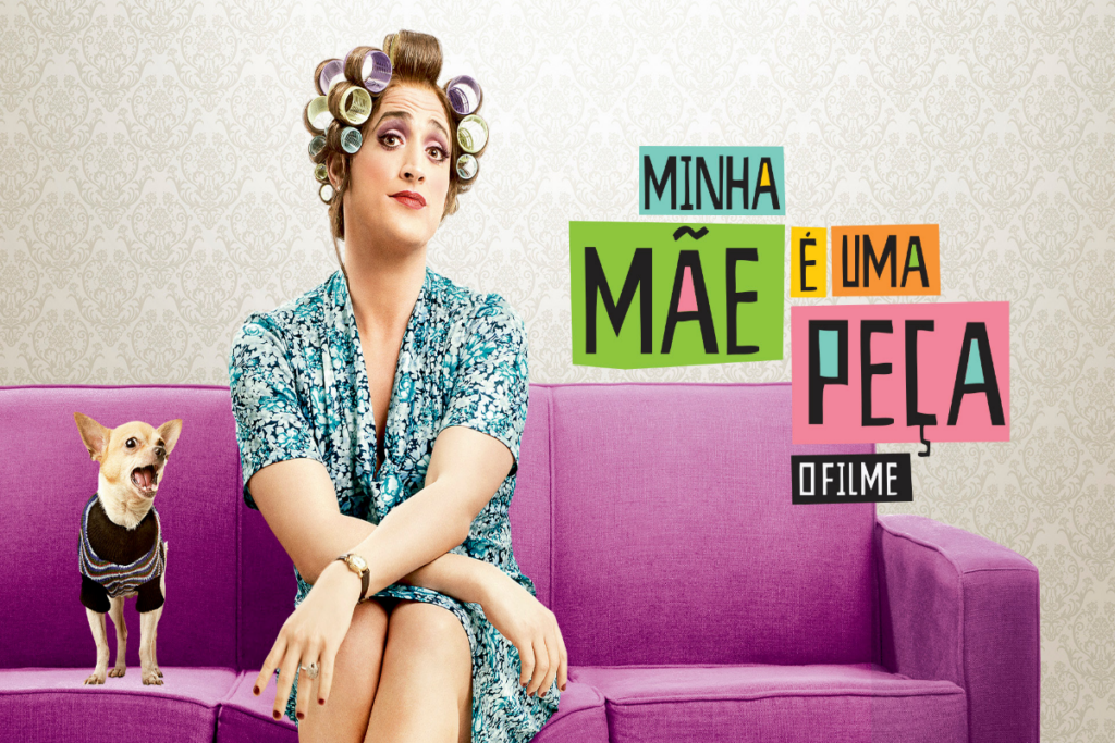 6 filmes de comédia sobre mães brasileiras 27 Mulher com bobes no cabelo, e usando um vestido estampado, sentada ao lado de um cachorro com roupa preta sentada em um sofá roxo e com o nome do filme ao lado na imagem