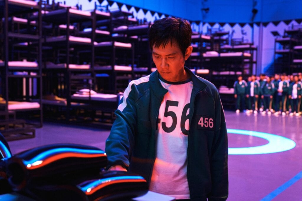 5 lançamentos imperdíveis da Netflix em junho de 2025 24 Homem usando um uniforme verde, com a numeração "456", colocando a mão em um objeto de metal